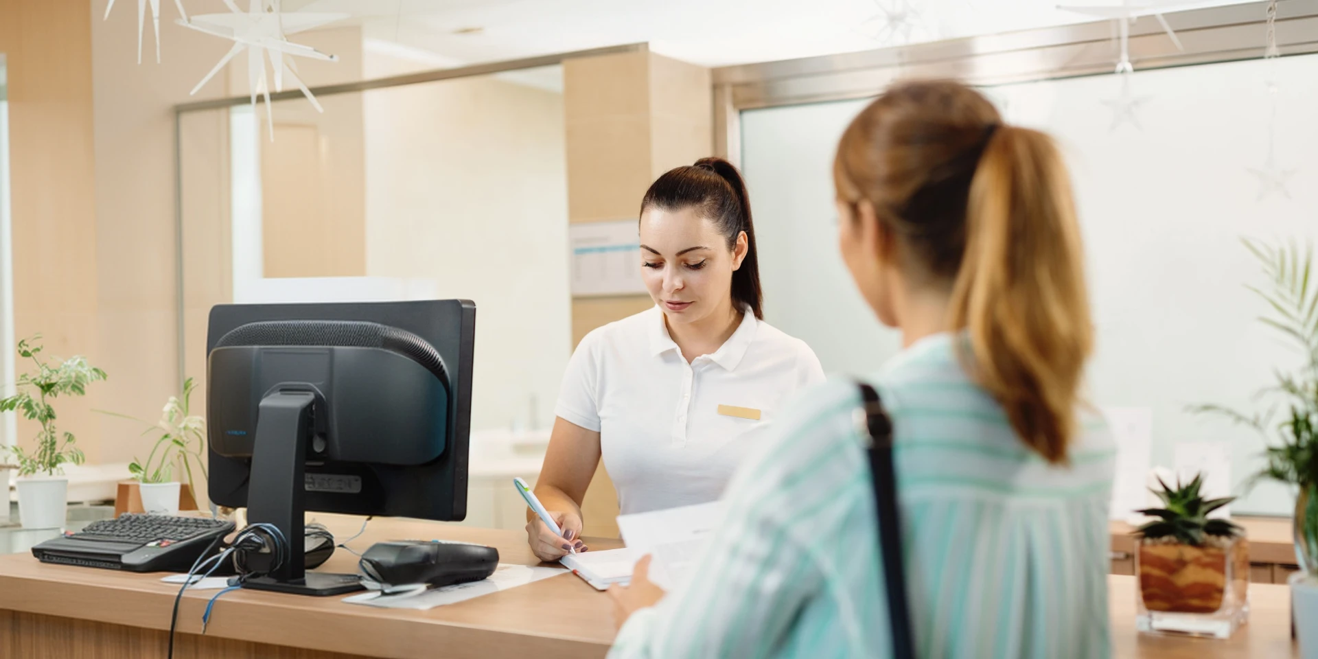 A team member greeting a patient at the front desk