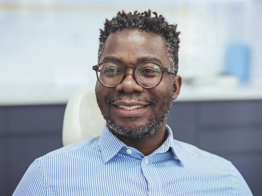 A smiling man with glasses in a striped shirt