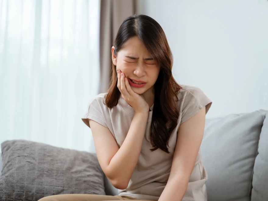 A woman holding her cheek in pain from a toothache