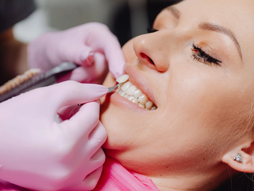 A smiling woman having her teeth checked by a dental team member