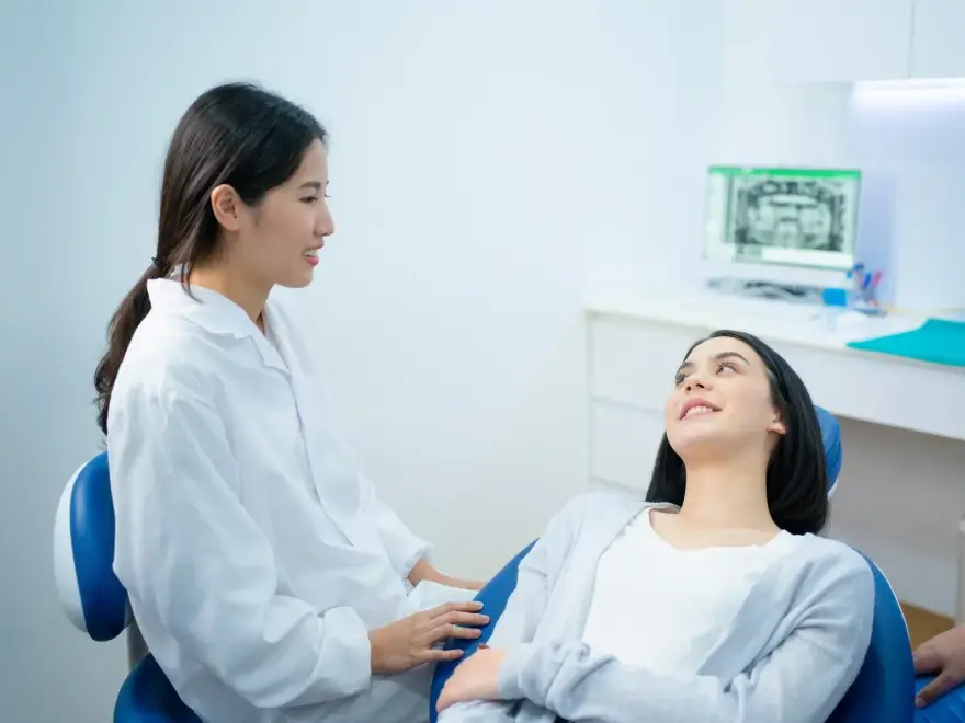 A dentist talking with a patient seated in the dental chair