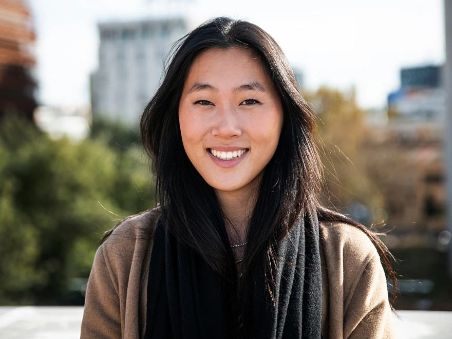 A smiling woman with long dark hair outdoors