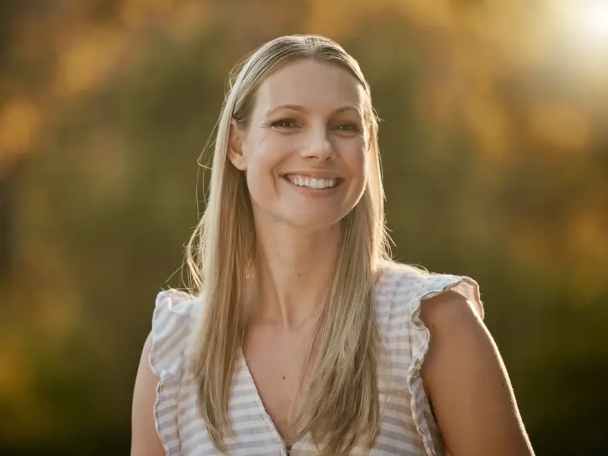 A smiling woman outdoors in warm light