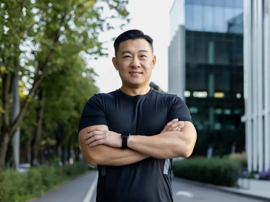 A confident man standing outdoors with his arms crossed