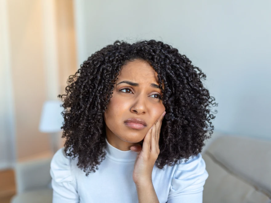 A woman holding her cheek in pain from a toothache