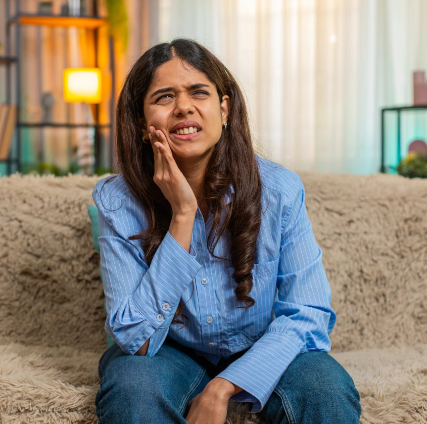 A woman wincing in discomfort while holding her cheek