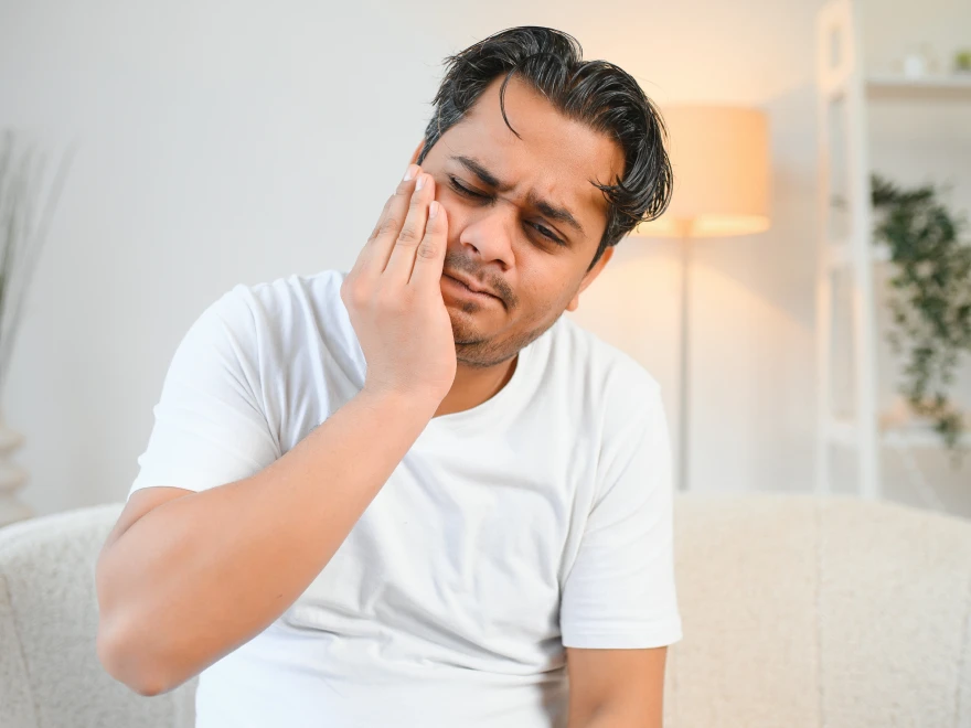 A man holding his cheek in pain from a toothache