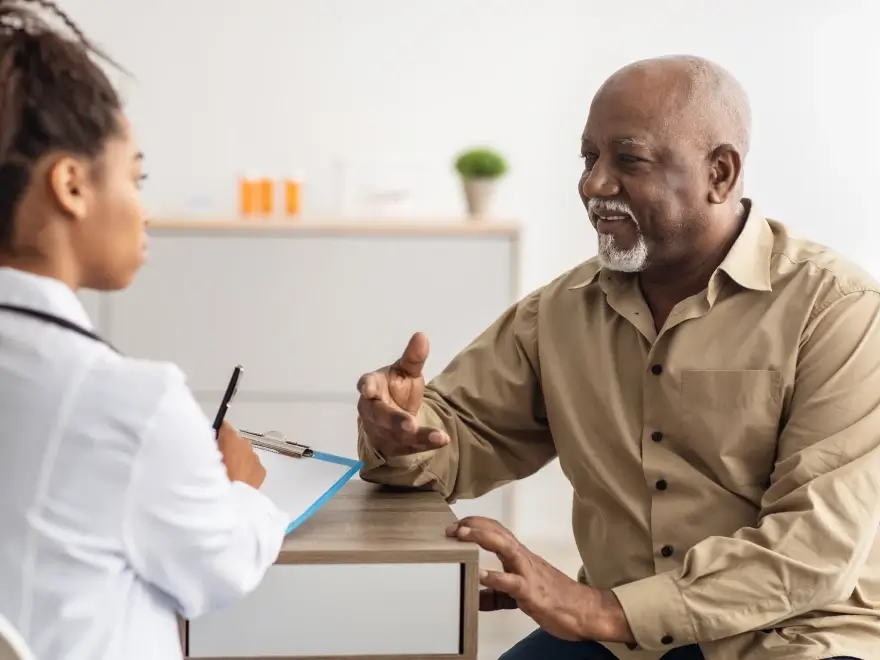 An older man talking with his dentist at a desk