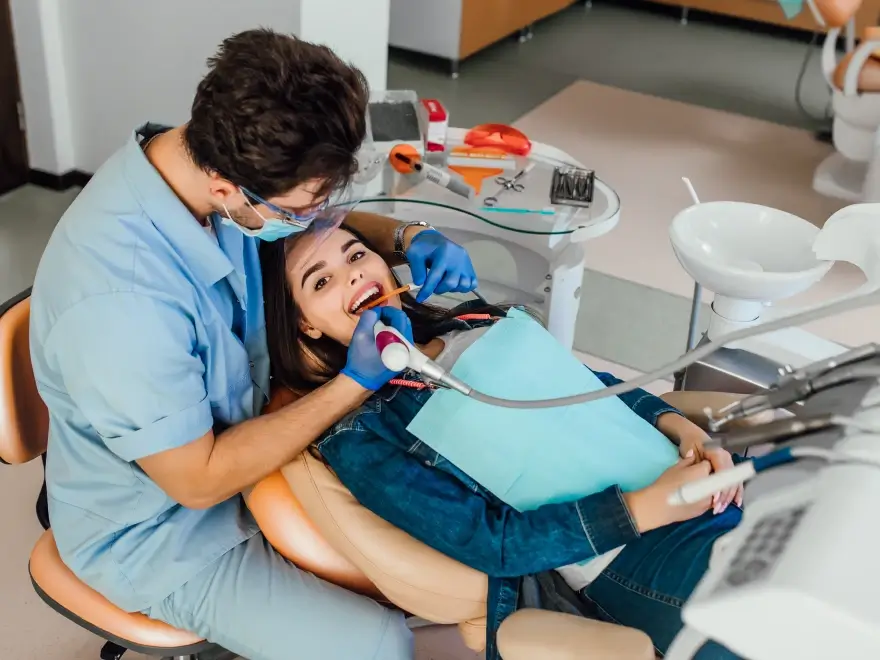 A dentist working on a patient reclined in the dental chair
