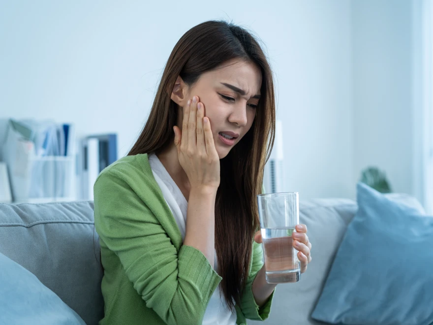 A woman holding her cheek because of tooth discomfort