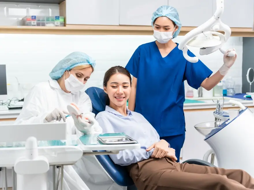 A patient smiling in the chair with two dental team members