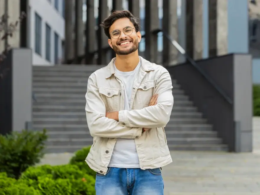 A smiling young man in a jacket standing outside