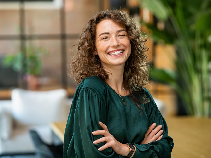 A smiling woman with curly hair in a green blouse