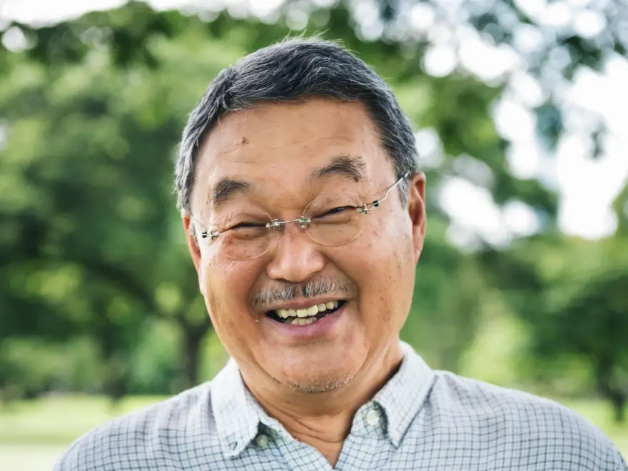 A smiling older man with glasses outdoors