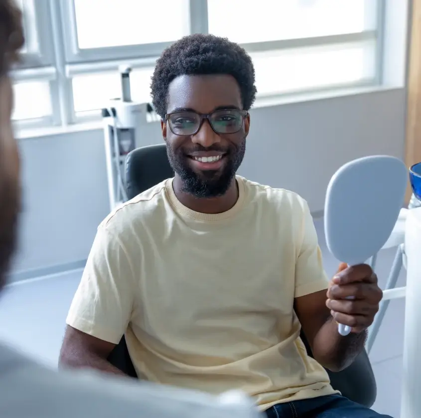 A smiling patient holding a hand mirror