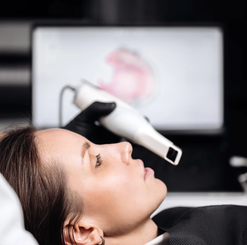 A woman reclined with her head back while a dentist uses an intraoral scanner