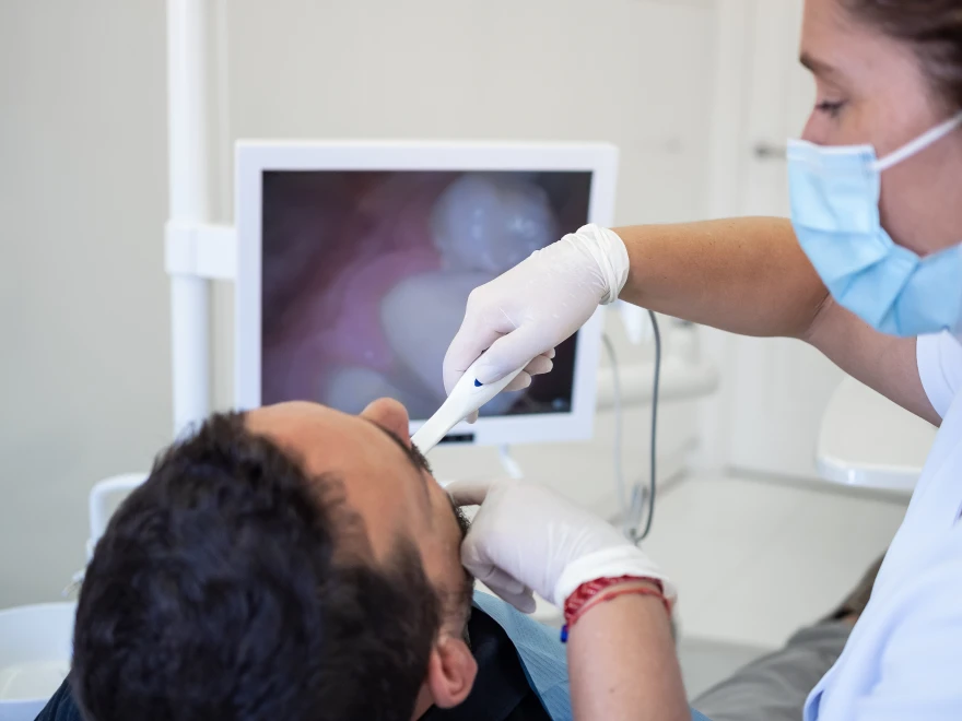 A dentist using an intraoral camera, with the live image on a chairside screen